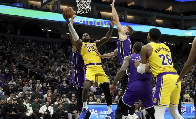 Los Angeles Lakers forward LeBron James (23) shoots against Sacramento Kings center Domantas Sabonis, center top right, during the first half of an NBA basketball game in Sacramento, Calif., Thursday, Dec. 19, 2024. (AP Photo/Jed Jacobsohn)