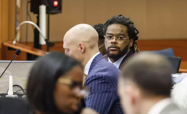 Shannon Stillwell, center back, sits with his attorney, Max Schardt, left, as he looks at the prosecutors during the Young Thug trial at Fulton County Courthouse in Atlanta on Tuesday, Nov. 26, 2024. (Miguel Martinez/Atlanta Journal-Constitution via AP)