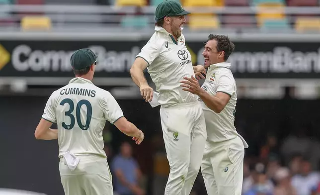 Australia's Mitchell Starc, right, Mitchell Marsh, center, and Australia's captain Pat Cummins celebrates after the dismissal of India's Shubman Gill during play on day three of the third cricket test between India and Australia at the Gabba in Brisbane, Australia, Monday, Dec. 16, 2024. (AP Photo/Pat Hoelscher)