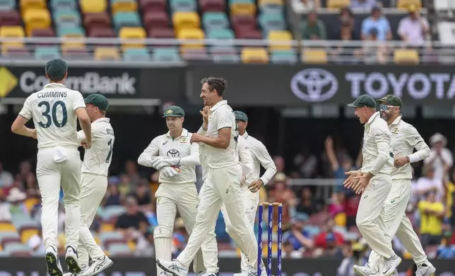 Australia's Mitchell Starc, center without cap, celebrates with teammates after the dismissal of India's Yashasvi Jaiswal during play on day three of the third cricket test between India and Australia at the Gabba in Brisbane, Australia, Monday, Dec. 16, 2024. (AP Photo/Pat Hoelscher)