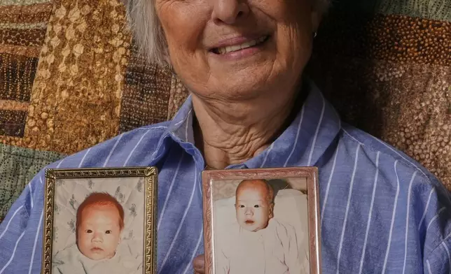 Peg Reif holds pictures of her children adopted from South Korea in the 1980s in her home Tuesday, Dec. 17, 2024 in Platteville, Wis. (AP Photo/Morry Gash)