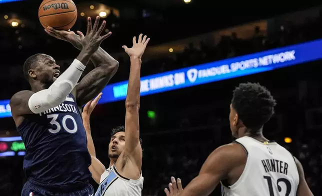 Minnesota Timberwolves forward Julius Randle (30) shoots into Atlanta Hawks forward De'Andre Hunter (12) during the first half of an NBA basketball game, Monday, Dec. 23, 2024, in Atlanta. (AP Photo/Mike Stewart)