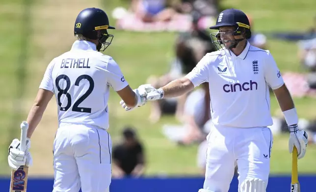 England's Jacob Bethell and Joe Root gesture during play on day four of the third cricket test between England and New Zealand in Hamilton, New Zealand, Tuesday, Dec. 17, 2024. (Andrew Cornaga/Photosport via AP)