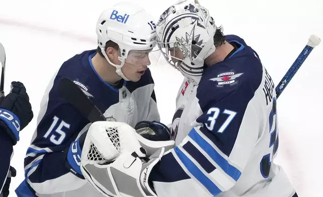 Winnipeg Jets goaltender Connor Hellebuyck (37) is congratulated by Rasmus Kupari (15) after a 4-3 victory against the San Jose Sharks during the third period of an NHL hockey game in San Jose, Calif., Tuesday, Dec. 17, 2024. (AP Photo/Tony Avelar)