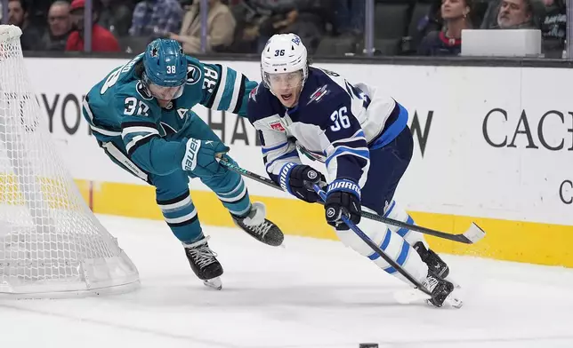 Winnipeg Jets center Morgan Barron (36) battles for the puck against San Jose Sharks defenseman Mario Ferraro (38) during the second period of an NHL hockey game in San Jose, Calif., Tuesday, Dec. 17, 2024. (AP Photo/Tony Avelar)