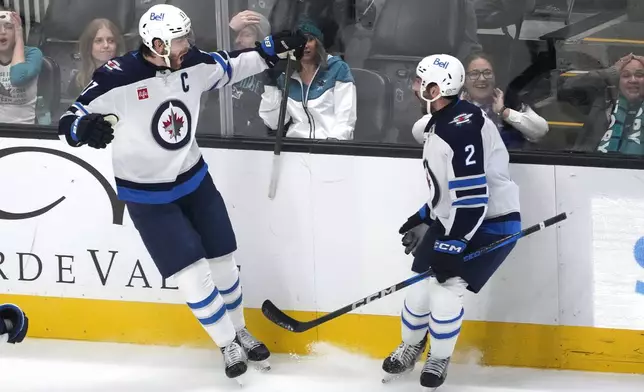 Winnipeg Jets center Adam Lowry, left, celebrates with teammate Dylan DeMelo (2) after scoring a goal against the San Jose Sharks during the third period of an NHL hockey game in San Jose, Calif., Tuesday, Dec. 17, 2024. Winnipeg won 4-3. (AP Photo/Tony Avelar)