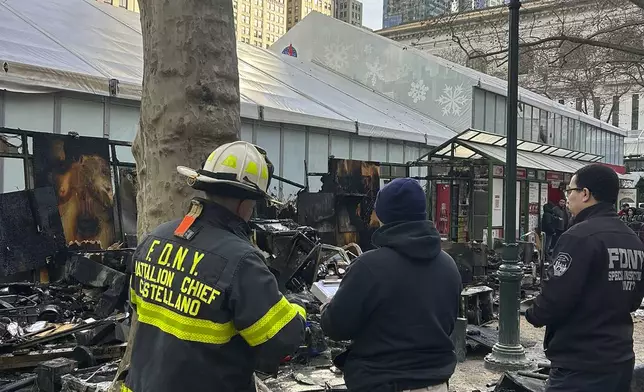 This image provided by the Fire Department of New York, FDNY personnel investigates the aftermath of a fire at an outdoor holiday market in Bryant Park on Friday, Dec. 27, 2024 in New York. (FDNY via AP)