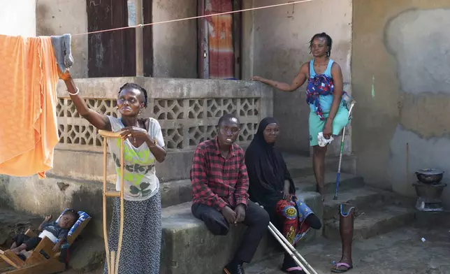 Amputees sit in front of their dwellings built by foreign NGOs in Freetown, Sierra Leone, Wednesday, Sept. 25, 2024. (AP Photo/Jack Thompson)