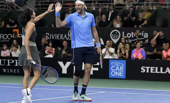 Former tennis player Gabriela Sabatini and Juan Martin Del Potro high-five during an exhibition doubles tennis match against Serbia's Novak Djokovic and Gisela Dulko in Buenos Aires, Argentina, Sunday, Dec. 1, 2024. (AP Photo/Gustavo Garello)