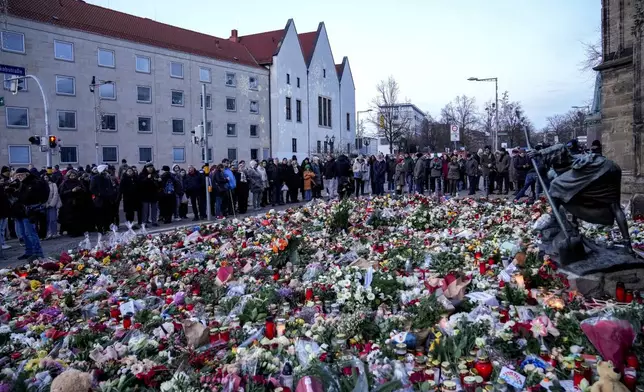 People lay flowers and lit candles in front of the Johannis church close to the Christmas market, where a car drove into a crowd on Friday evening, in Magdeburg, Germany, Sunday, Dec. 22, 2024. (AP Photo/Ebrahim Noroozi)