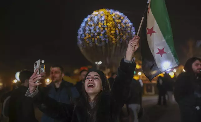 A girl hold a Syrian 'revolutionary' flag during a Christmas celebration early Sunday Dec. 22, 2024 in Damascus, Syria.(AP Photo/Ghaith Alsayed)