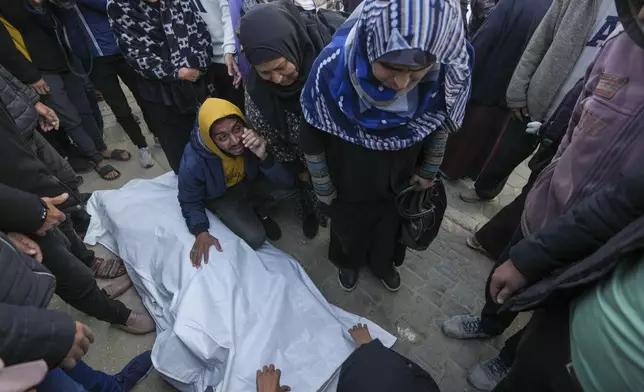 Relatives and neighbours mourn over the body of one of the victims of an Israeli strike on a hom4 late Saturday as they are prepared for the funeral outside the Al-Aqsa Martyrs Hospital in Deir al-Balah Sunday, Dec. 22, 2024. At least eight people were killed according to the hospital which received the bodies.(AP Photo/Abdel Kareem Hana)