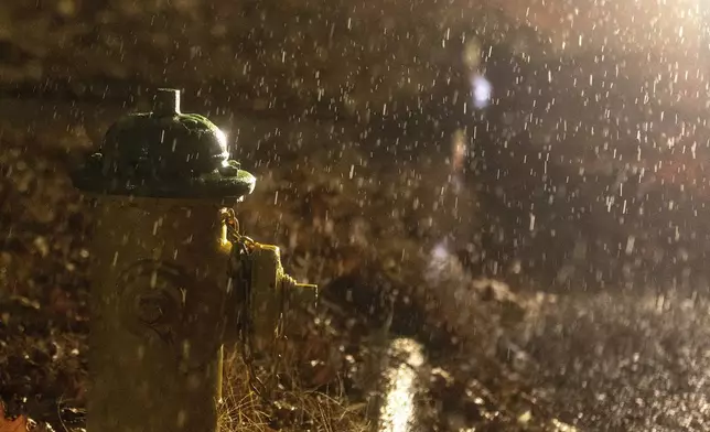 Headlights from a stranded motorist highlight freezing rain that coated surfaces in Omaha, Neb. on Friday, Dec. 13, 2024. (Chris Machian/Omaha World-Herald via AP)