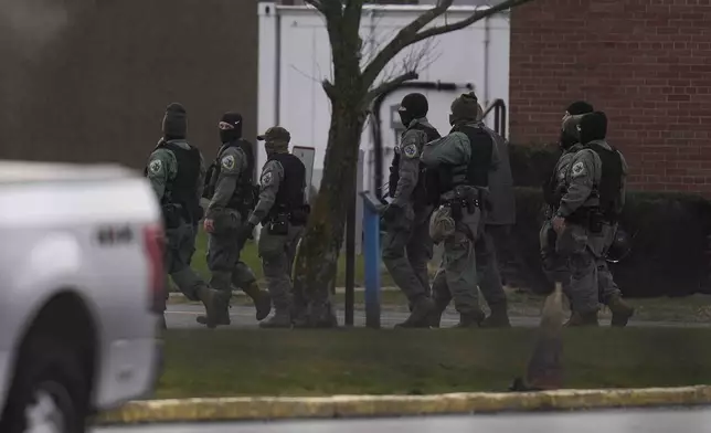 Police officers walk outside of Indiana State Prison on Tuesday, Dec. 17, 2024, in Michigan City, Ind., where, barring last-minute court action or intervention by Gov. Eric Holcomb, Joseph Corcoran, 49, convicted in the 1997 killings of his brother and three other people, is scheduled to be put to death by lethal injection before sunrise Wednesday, Dec. 18. (AP Photo/Erin Hooley)