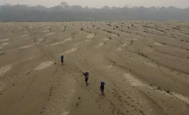 FILE - Residents transport drinking water from Humaita to the Paraizinho community, along the dry Madeira River, a tributary of the Amazon River, amid a drought, Amazonas state, Brazil, Sunday, Sept. 8, 2024. (AP Photo/Edmar Barros, File)