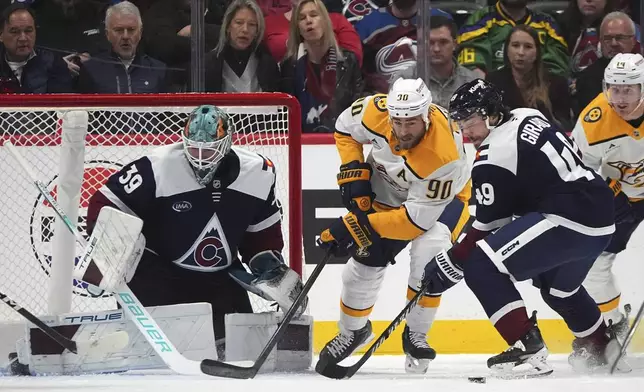 Nashville Predators center Ryan O'Reilly, center, struggles to control the puck as Colorado Avalanche goaltender Mackenzie Blackwood, left, and defenseman Samuel Girard cover in the first period of an NHL hockey game Saturday, Dec. 14, 2024, in Denver. (AP Photo/David Zalubowski)