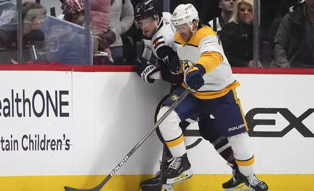 Nashville Predators center Jonathan Marchessault, front, pins Colorado Avalanche center Parker Kelly to the boards while pursuing the puck in the second period of an NHL hockey game Saturday, Dec. 14, 2024, in Denver. (AP Photo/David Zalubowski)