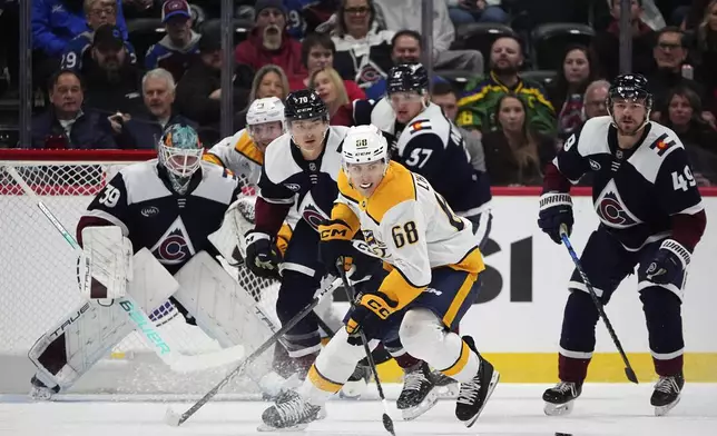 Nashville Predators left wing Zachary L'Heureux, front, pursues the puck while, from back left, Colorado Avalanche goaltender Mackenzie Blackwood, defenseman Sam Malinski, center Casey Mittelstadt and defenseman Samuel Girard cover in the first period of an NHL hockey game Saturday, Dec. 14, 2024, in Denver. (AP Photo/David Zalubowski)