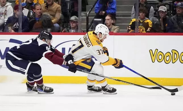 Nashville Predators defenseman Nick Blankenburg, right, collects the puck as Colorado Avalanche center Ivan Ivan defends in the first period of an NHL hockey game Saturday, Dec. 14, 2024, in Denver. (AP Photo/David Zalubowski)