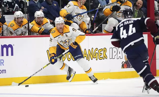 Nashville Predators center Steven Stamkos, left, collects the puck as Colorado Avalanche defenseman Calvin de Haan covers in the second period of an NHL hockey game Saturday, Dec. 14, 2024, in Denver. (AP Photo/David Zalubowski)