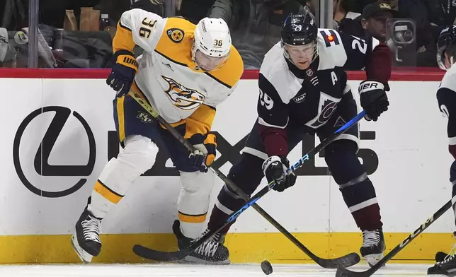 Nashville Predators left wing Cole Smith, left, fights to control the puck with Colorado Avalanche center Nathan MacKinnon in the second period of an NHL hockey game Saturday, Dec. 14, 2024, in Denver. (AP Photo/David Zalubowski)