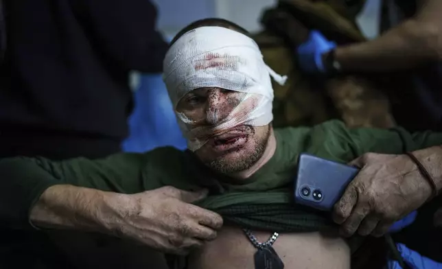 An injured Ukrainian serviceman takes off his shirt after arriving from the battlefield at Medical Service "Ulf" of the 108th Separate Battalion "Da Vinci Wolves" on Pokrovsk direction, Ukraine, Monday, Dec. 23, 2024. (AP Photo/Evgeniy Maloletka)