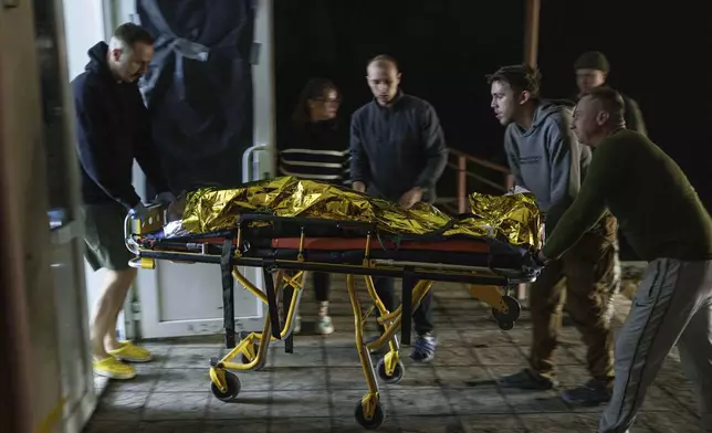 Medics haul an injured Ukrainian serviceman on a stretcher from an ambulance at Medical Service "Ulf" of the 108th Separate Battalion "Da Vinci Wolves" on Pokrovsk direction, Ukraine, Tuesday, Dec. 24, 2024. (AP Photo/Evgeniy Maloletka)