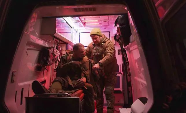 A medic helps an injured Ukrainian serviceman walk out of an ambulance at Medical Service "Ulf" of the 108th Separate Battalion "Da Vinci Wolves" on Pokrovsk direction, Ukraine, Tuesday, Dec. 24, 2024. (AP Photo/Evgeniy Maloletka)