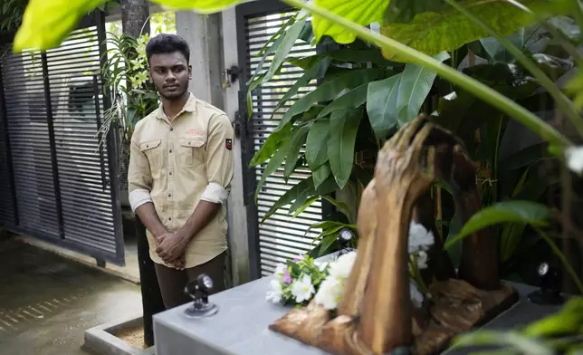 Jayarasa Abilash, known as Baby 81 after he was swept away by the 2004 Indian ocean tsunami, stands in front of a monument built in memory of tsunami victims outside his residence in Kurukkalmadam, Sri Lanka, Tuesday, Dec. 17, 2024. (AP Photo/Eranga Jayawardena)