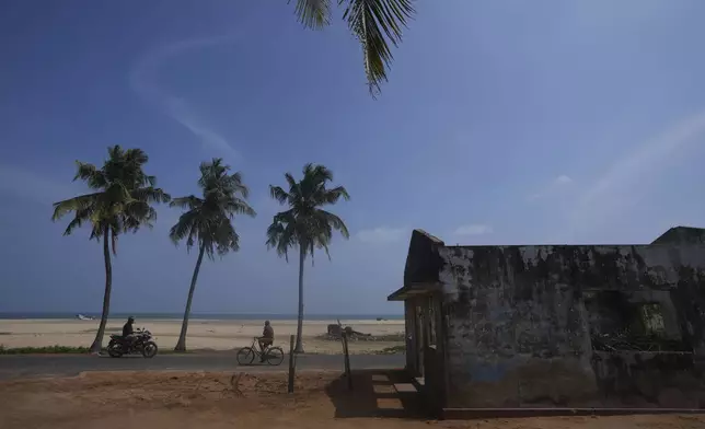 People ride past the surroundings of Jayarasa Abilash, known as Baby 81 after he was swept away by the 2004 Indian ocean tsunami, in Kalmunai, Sri Lanka, Tuesday, Dec. 17, 2024. (AP Photo/Eranga Jayawardena)