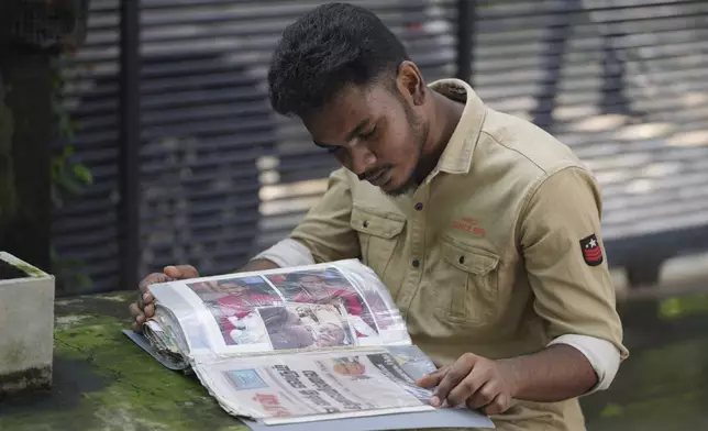 Jayarasa Abilash, known as Baby 81 after he was swept away by the 2004 Indian ocean tsunami, goes through his photo album at his residence in Kurukkalmadam, Sri Lanka, Tuesday, Dec. 17, 2024. (AP Photo/Eranga Jayawardena)