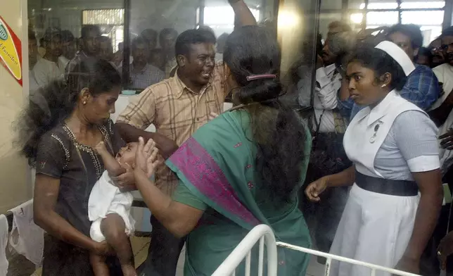 FILE - Jenita Jayarasa, left, the mother claimant of the infant dubbed "Baby 81" holds the child and father claimant Murugupillai Jayarasa, center, shouts as a doctor, center, tries to prevent them from taking the infant, inside a ward at a hospital in Kalmunai, about 210 kilometers (131 miles) east of Colombo, Sri Lanka, Wednesday, Feb. 2, 2005. (AP Photo/Rafiq Maqbool, File)