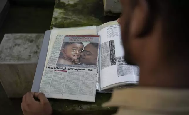 Jayarasa Abilash, known as Baby 81 after he was swept away by the 2004 Indian ocean tsunami, goes through his photo album at his residence in Kurukkalmadam, Sri Lanka, Tuesday, Dec. 17, 2024. (AP Photo/Eranga Jayawardena)