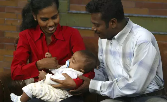 FILE - Jayarasa Abilash, popularly known as 'Baby 81", naps in the arms of his mother Jenita, as his father, Murugupillai, helps make him comfortable during a photo opportunity in New York, Wednesday, March 2, 2005. (AP Photo/Mary Altaffer, File)