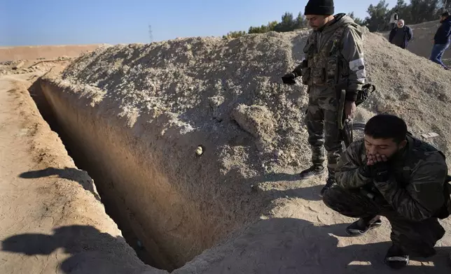 Syrian fighters from rebel group, observe a location identified as a mass grave for detainees killed under rule of Bashar Assad in Najha, south of Damascusn Najha, south of Damascus, Syria, Tuesday, Dec. 17, 2024. (AP Photo/Hussein Malla)