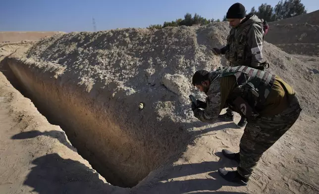 Syrian fighters from rebbel group, observe a location identified as a mass grave for detainees killed under rule of Bashar Assad in Najha, south of Damascusn Najha, south of Damascus, Syria, Tuesday, Dec. 17, 2024. (AP Photo/Hussein Malla)