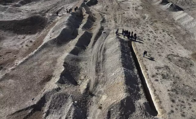 Activists from The U.S.-based Syrian Emergency Task Force and people observe a location identified as a mass grave for detainees killed under rule of Bashar Assad in Najha, south of Damascus, Syria, Tuesday, Dec. 17, 2024. (AP Photo/Hussein Malla)