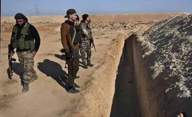 Syrian fighters from rebel group, observe a location identified as a mass grave for detainees killed under rule of Bashar Assad in Najha, south of Damascusn Najha, south of Damascus, Syria, Tuesday, Dec. 17, 2024. (AP Photo/Hussein Malla)