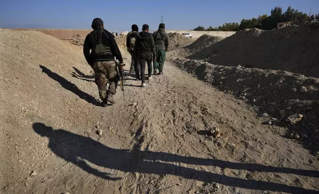 Syrian fighters from rebel group, arrive at a location identified as a mass grave for detainees killed under rule of Bashar Assad in Najha, south of Damascus, Syria, Tuesday, Dec. 17, 2024. (AP Photo/Hussein Malla)