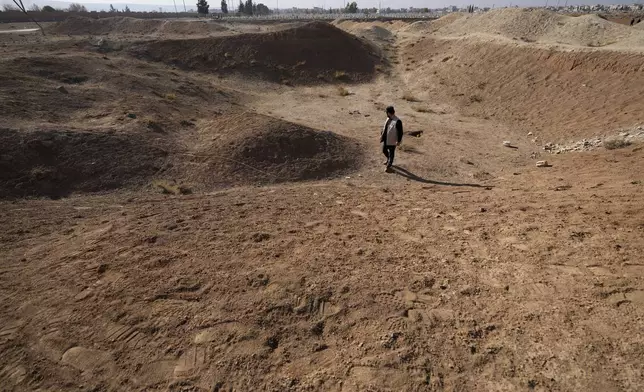 An activist from The U.S.-based Syrian Emergency Task Force and people observes a location identified as a mass grave for detainees killed under rule of Bashar Assad in Najha, south of Damascus, southern Damascus, Syria, Tuesday, Dec. 17, 2024. (AP Photo/Hussein Malla)