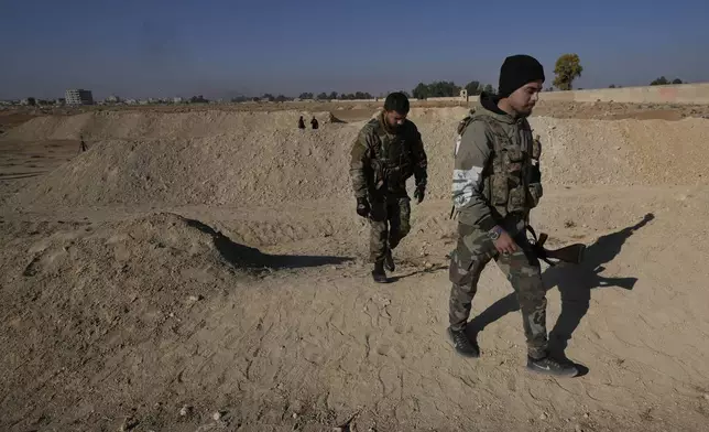 Syrian fighters from a rebel group, arrive at a location identified as a mass grave for detainees killed under rule of Bashar Assad in Najha, south of Damascus, southern Damascus, Syria, Tuesday, Dec. 17, 2024. (AP Photo/Hussein Malla)