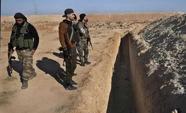 Syrian rebels observe a location identified as a mass grave for detainees killed under the rule of Bashar Assad in Najha, south of Damascus, Syria, Tuesday, Dec. 17, 2024. (AP Photo/Hussein Malla)