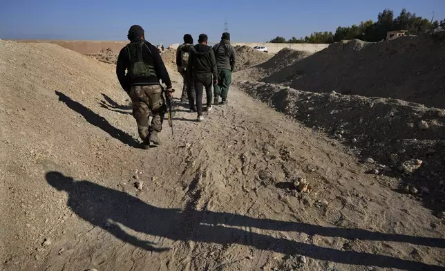 Syrian rebels arrive at a location identified as a mass grave for detainees killed under the rule of Bashar Assad in Najha, south of Damascus, Syria, Tuesday, Dec. 17, 2024. (AP Photo/Hussein Malla)