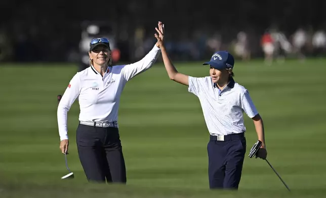 Annika Sorenstam, left, congratulates her son Will McGee after his shot to the 18th green during the first round o the PNC Championship golf tournament, Saturday, Dec. 21, 2024 in Orlando, Fla. (AP Photo/Phelan M. Ebenhack)