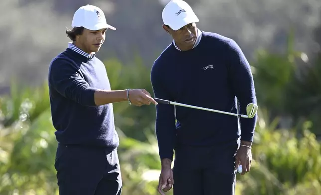 Tiger Woods, right, and his son Charlie Woods discuss their putt on the third green during the first round of the PNC Championship golf tournament, Saturday, Dec. 21, 2024 in Orlando. (AP Photo/Phelan M. Ebenhack)