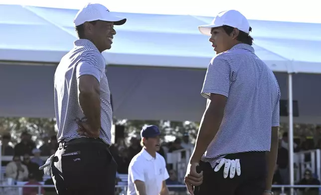 Tiger Woods, left, talks with his son Charlie Woods, right, after finishing on the 18th green during the first round of the PNC Championship golf tournament, Saturday, Dec. 21, 2024, in Orlando. (AP Photo/Phelan M. Ebenhack)