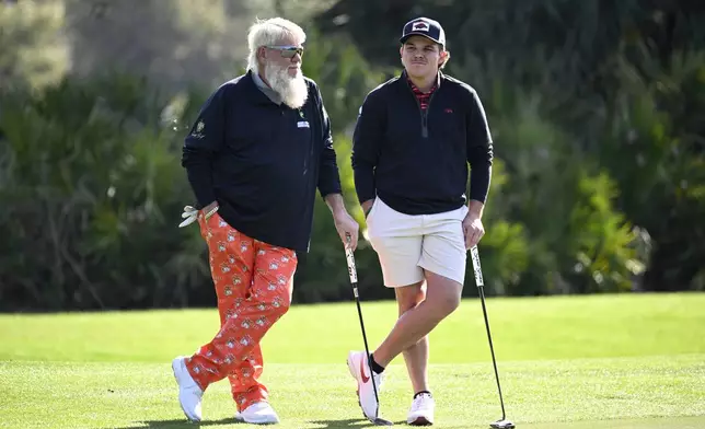 John Daly, left, and his son John Daly II wait to putt on the third green hole during the first round of the PNC Championship golf tournament, Saturday, Dec. 21, 2024, in Orlando, Fla. (AP Photo/Phelan M. Ebenhack)