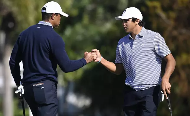 Charlie Woods, right, gets a fist bump from his father, Tiger Woods after making their putt on the fourth green during the first round of the PNC Championship golf tournament, Saturday, Dec. 21, 2024 in Orlando. (AP Photo/Phelan M. Ebenhack)