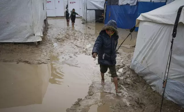 A boy walks barefoot through the mud after overnight rainfall at the refugee tent camp for displaced Palestinians in Deir al-Balah, central Gaza Strip, Tuesday, Dec. 31, 2024. (AP Photo/Abdel Kareem Hana)