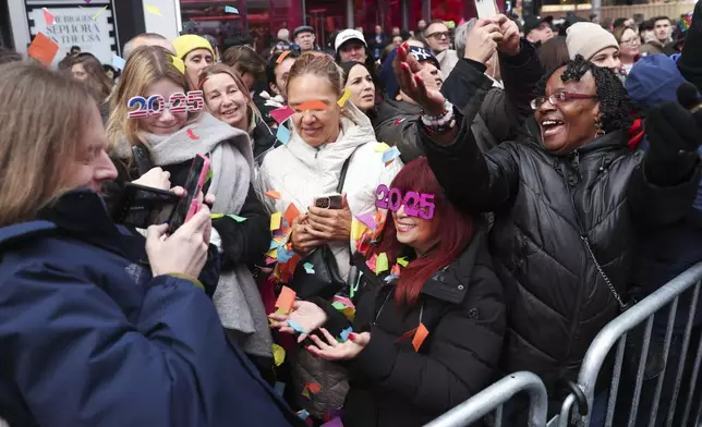 People in the crowd pose for photos with confetti ahead of New Year's Eve in Times Square, Sunday, Dec. 29, 2024, in New York. (AP Photo/Heather Khalifa)